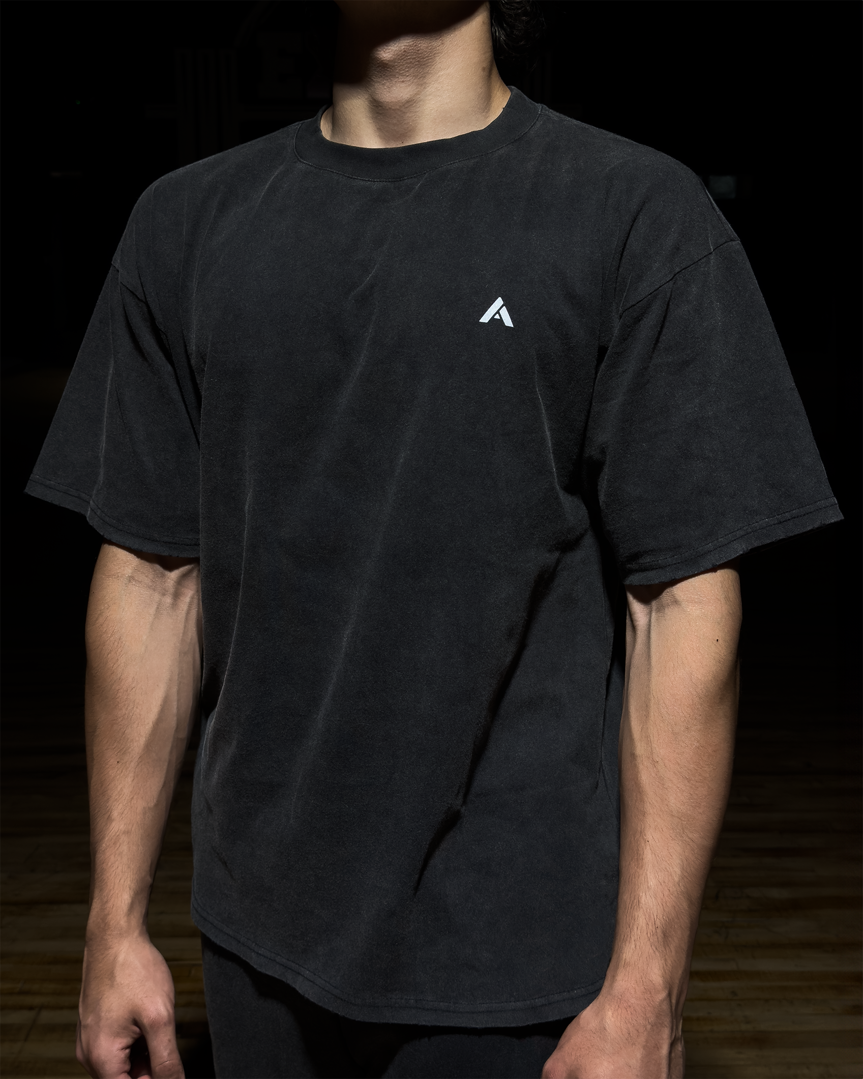 Person wearing a black t-shirt with a white simplistic letter "A" logo on a dark background.